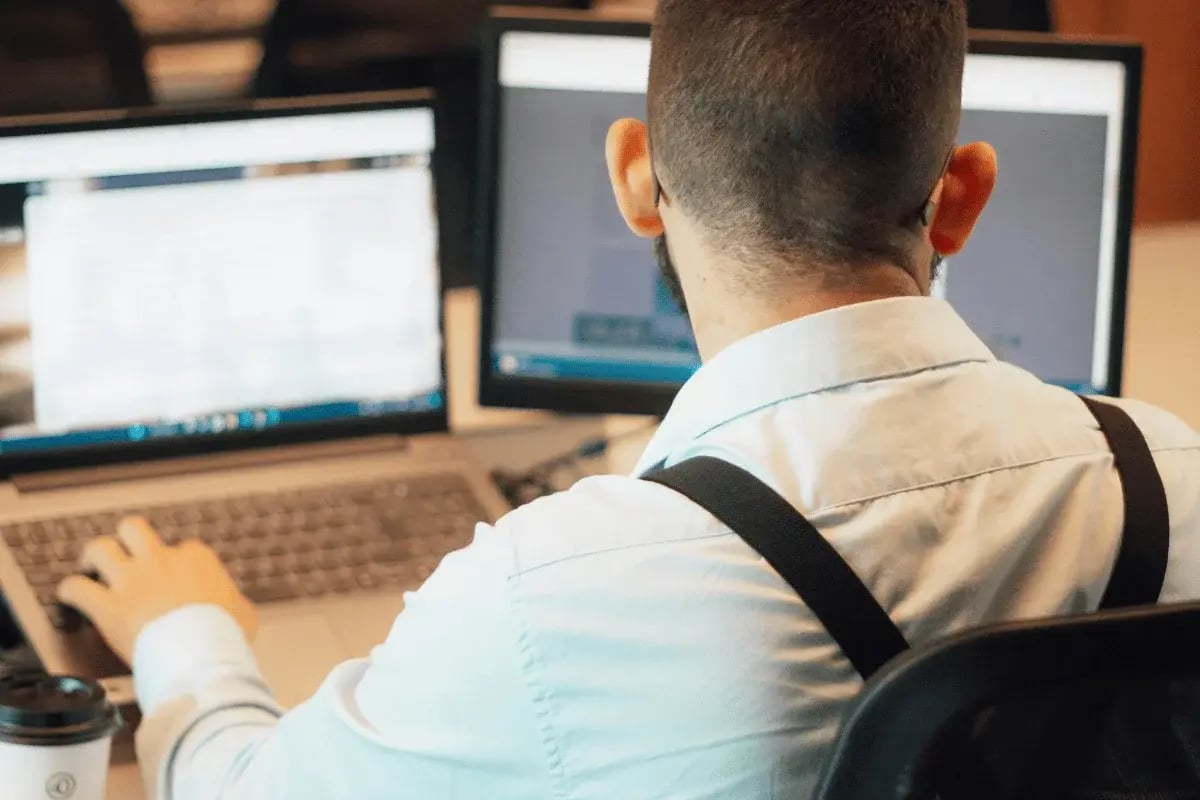 Professional analyzing information across multiple computer screens.