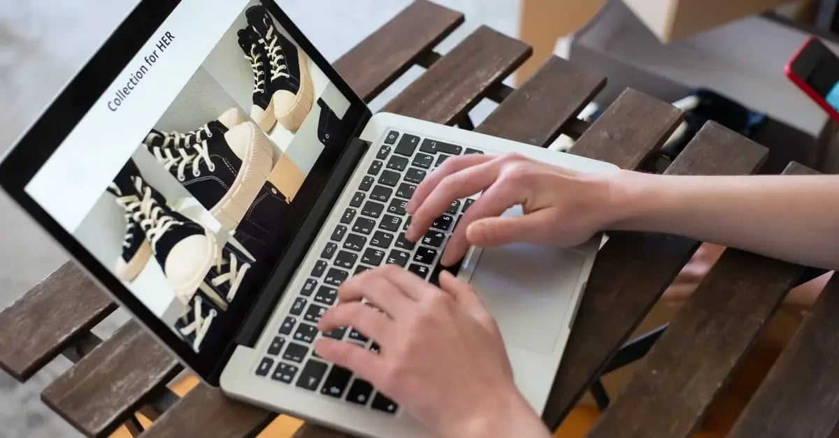 Person typing on laptop displaying amazon product variations with shoes on wooden desk setup.