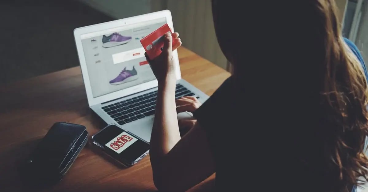 Woman viewing Amazon product listings on laptop while holding credit card, demonstrating Amazon PPC strategy research.